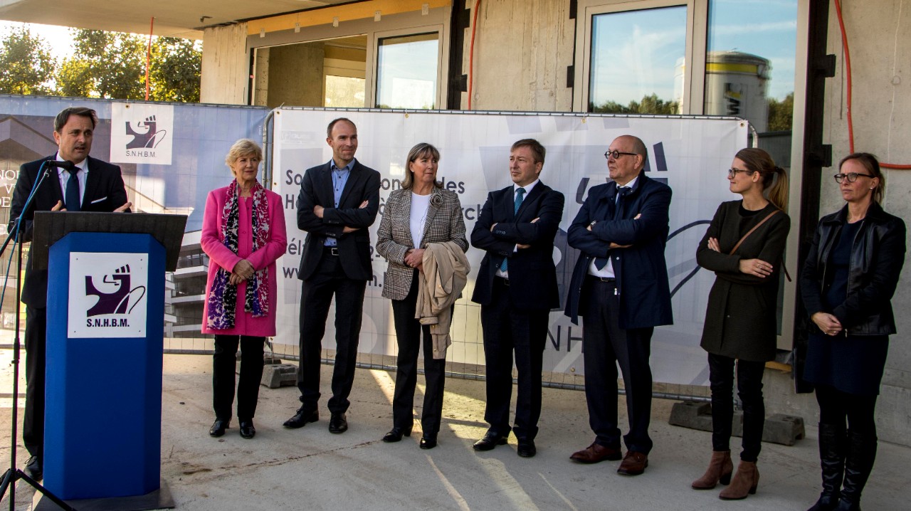Le Premier ministre, Xavier Bettel, ensemble avec le ministre du Logement, Marc Hansen, entourés de représentants communaux de la Ville de Luxembourg et des responsables du projet, lors de la fête du bouquet de la résidence Vela au Kirchberg.