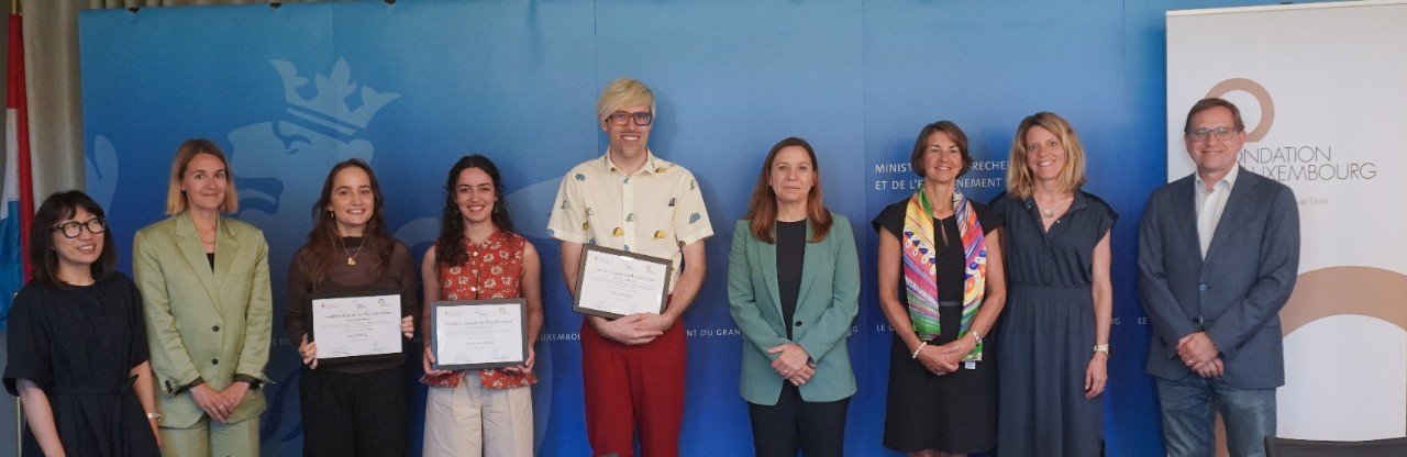 (de g. à dr.) Anouk Wies, Université du Luxembourg; Manon Kirsch, ministère de la Recherche et de l’Enseignement supérieur ; Lara Schmitz, lauréate ; Uğur Darya Eroğlu, lauréate ; Gilles Schneider, lauréat ; Stéphanie Obertin, ministre de la Recherche et de l’Enseignement supérieur ; Tonika Hirdman, directrice générale Fondation de Luxembourg ; Stéphanie Schott, ministère de la Recherche et de l’Enseignement supérieur ; Léon Diederich, ministère de la Recherche et de l’Enseignement supérieur